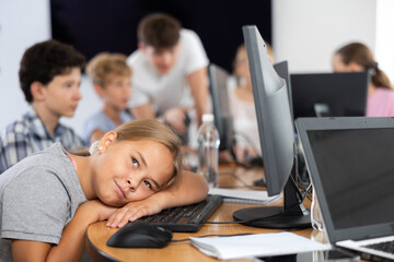 Girl student tired and lies down at computer desk during lesson