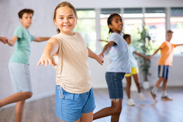 Positive preteen children learning to dance waltz in pairs in choreography class