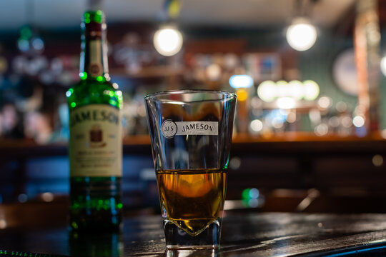 Branded glass with irish whiskey Jameson close-up on table on blurred background of irish pub. Ukraine, Zhytomyr, December, 11, 2023