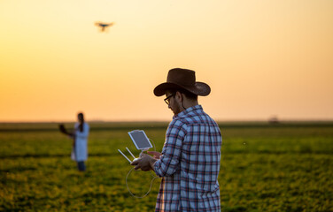 Fototapeta premium Farmer driving drone above farmland