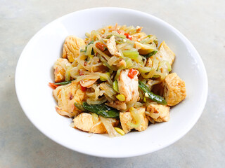 stir-fry chayote mixed with tofu and bean sprouts. Indonesia traditional food. Sayur welok atau labu siam dan tahu. spicy chayote cooked with tofu and bean sprouts in bowl on gray background. homemade