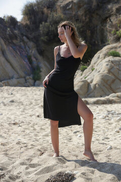Fashion outdoor portrait of female model in midi black camisole dress on the beach, summer vacation concept