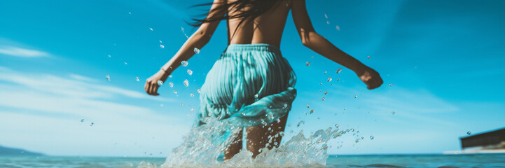 woman in bikini jumping in water. unfocused woman figure running into the sea, splashing water drops on focus. super wide header image.