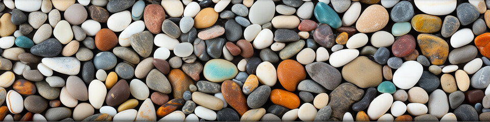 Fototapeta na wymiar long narrow panoramic view background multicolored sea polished stones, rolled pebbles on the seashore texture gems