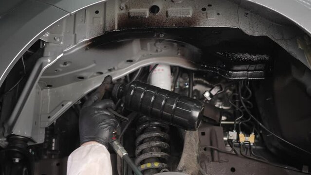 The master sprays an anti-corrosion compound on the bottom of the car. 