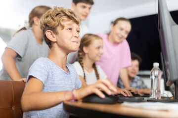 Fototapeta premium Curious underage boy engaged in IT training during computer courses for children