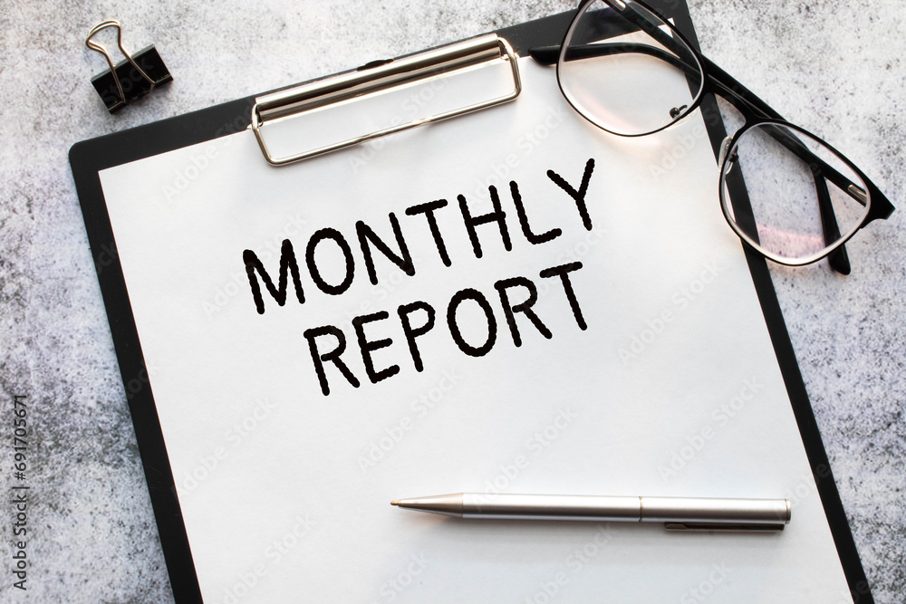 Poster monthly report text written on a paper clipboard with chart and calculator.