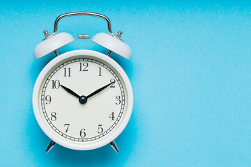 White Alarm Clock on Blue Background, Time Concept, Copy Space