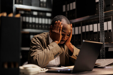 Exhausted african american investigator solving complex crime case in evening. Tired policeman...