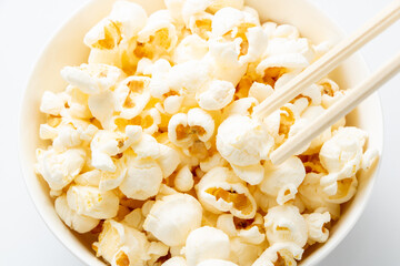 ポップコーンを箸で食べるイメージ。(白バック)
