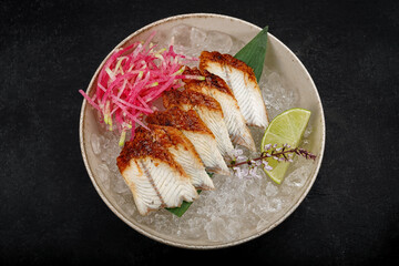 Eel sashimi with lime and ice on a bamboo leaf