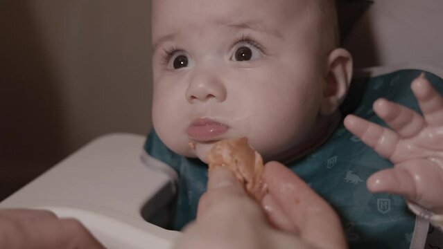 Adorable Baby Eating Salmon for the First Time. First Solid Food, 6 month old. White Caucasian Boy.