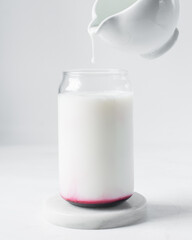 Pouring yogurt into can shaped glass on a marble tray, yoghurt being poured into novelty trendy glass cup