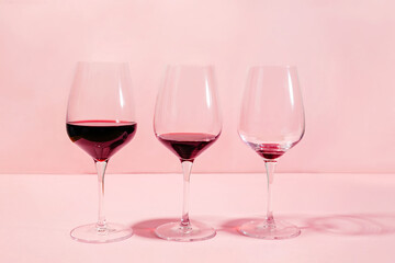 Mindful drinking and alcohol cutback concept. Three glasses with lowering levels of red wine poured - obrazy, fototapety, plakaty