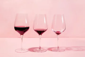 Schilderijen op glas Mindful drinking and alcohol cutback concept. Three glasses with lowering levels of red wine poured © Diana Vyshniakova