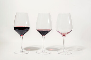 Three glasses with less amount of red wine poured in each, isolated on white. Mindful drinking and...