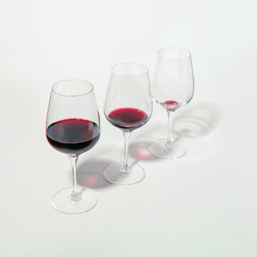 Three glasses with lowering levels of red wine poured, isolated on white. Mindful drinking and alcohol cutback.