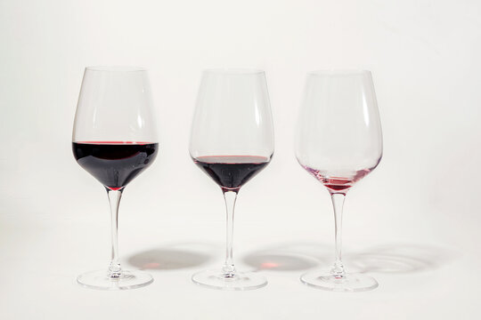 Three glasses with less amount of red wine poured in each, isolated on white. Mindful drinking and alcohol cutback.