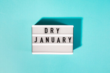 Text Dry January on the decorative lightbox isolated on blue background, mindful drinking - obrazy, fototapety, plakaty