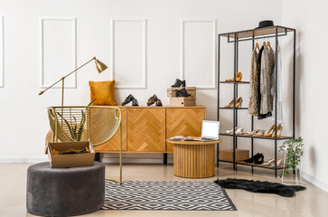 Interior of stylish boutique with clothes, shoes and modern laptop