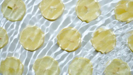 Slice of lemon underwater or in water with splashing and droplet top view flat lay on white background.