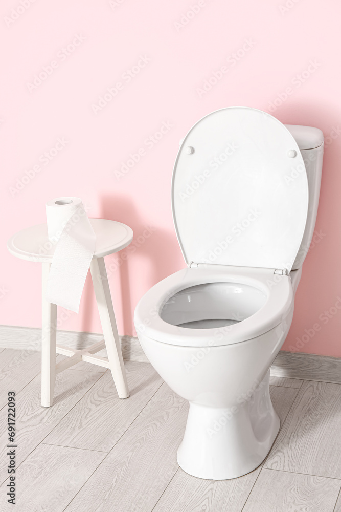 Wall mural Table with roll of paper and ceramic toilet bowl near color wall