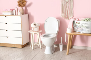 Stylish interior of modern restroom with ceramic toilet bowl and paper rolls