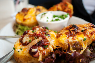 Loaded Baked Potato with Cheese and Accompaniments, Served with Sour Cream in an American Restaurant