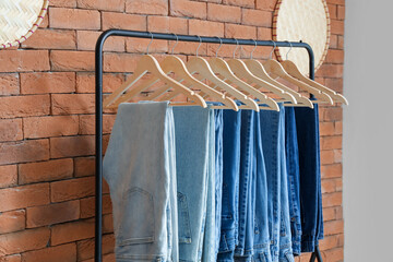 Rack with different jeans near brick wall - Powered by Adobe