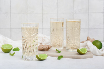 Glasses of fresh ginger beer with mint and lime on light background