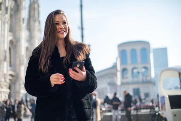 Zelfklevend Fotobehang Milaan Woman using her smartphone while walking in a city