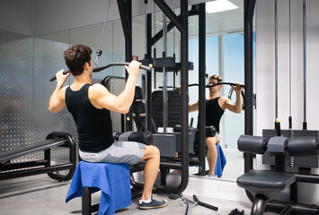 Man using a lat machine in a gym to train his shoulders and back