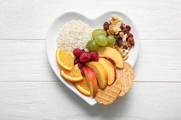 Plate with fresh healthy products on light wooden background. Diet concept