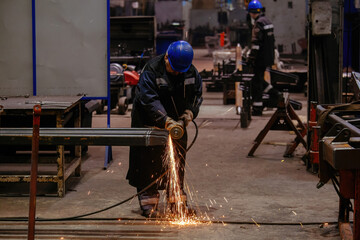 Worker grinding machine part in metalworking workshop