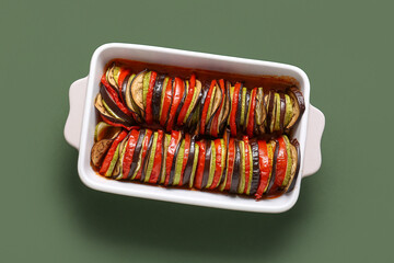 Baking dish of tasty Ratatouille on green background