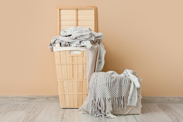 Laundry basket with dirty clothes near beige wall