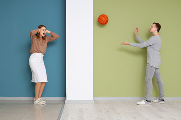 Young woman suffering from loud neighbour playing with ball at home