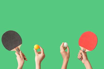 Female hands with ping pong rackets and balls on green background