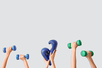 Female hands with dumbbells and boxing gloves on grey background