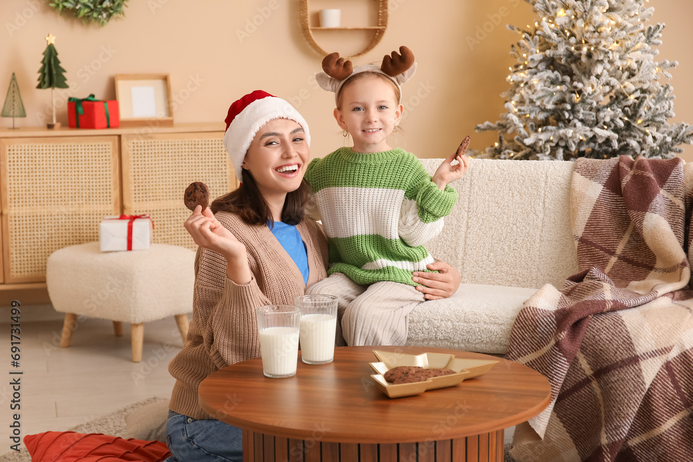 Sticker happy mother and her little daughter eating cookies with milk at home on christmas eve