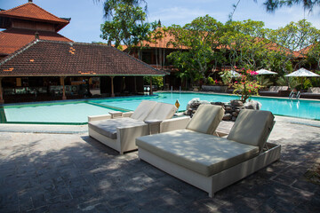 Typical Balinese swimming pool at a resort in Sanur, Bali with traditional buildings.