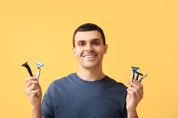 Handsome young man with razors on yellow background