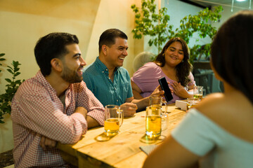 Group of happy friends talking after eating dinner at night