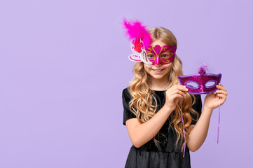 Funny little girl with carnival masks on lilac background