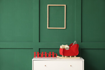 Christmas decor on chest of drawers and empty picture frame hanging on color wall