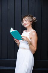A beautiful woman in a white dress is reading a book