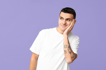 Handsome ashamed young man on lilac background