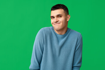 Handsome ashamed young man on green background