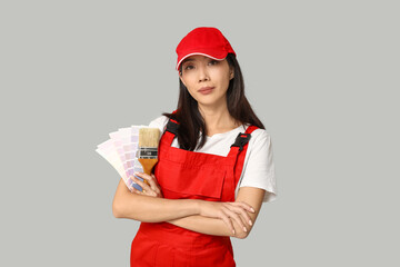 Female Asian painter with paint color palettes and brush on grey background