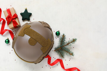 Composition with military helmet, Christmas decorations and gift box on light background